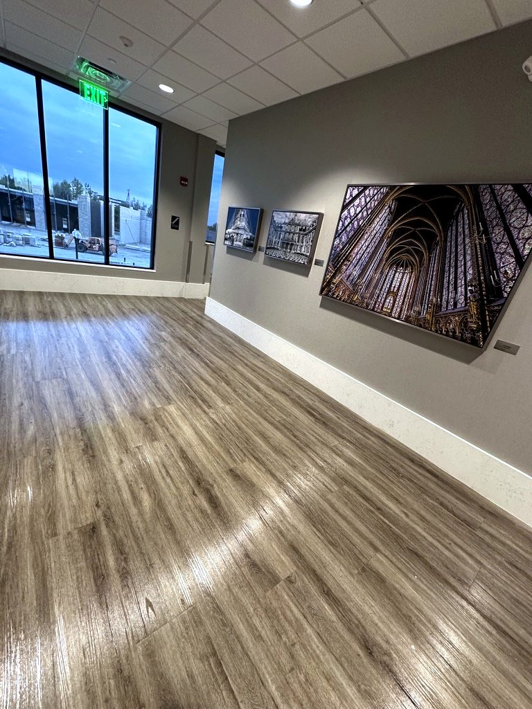 Medical office hallway in Munster, Indiana, with polished plank floors and framed art, after our post construction cleaning