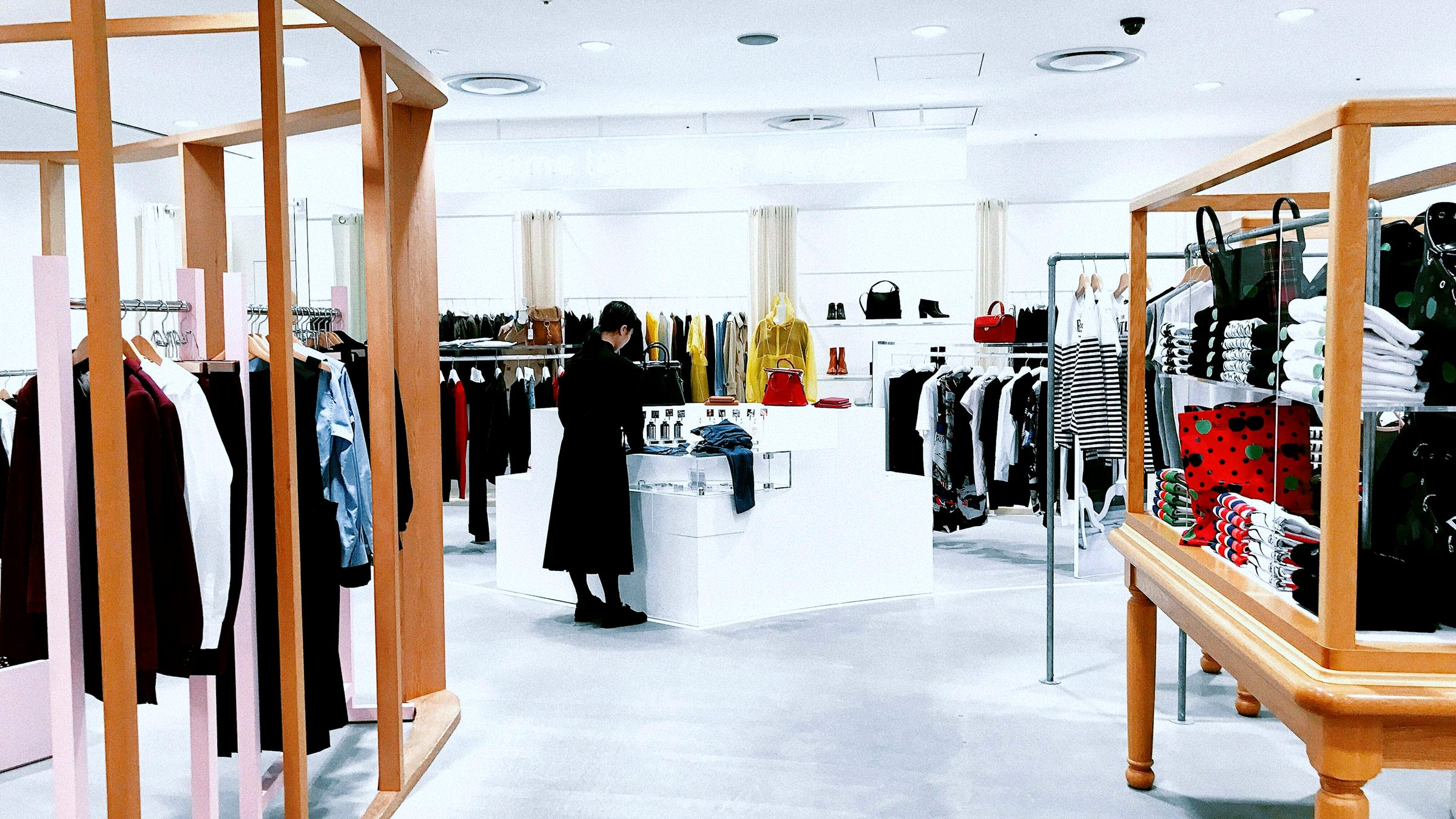 A bright clothing store sales floor with racks, display tables and a clean floor