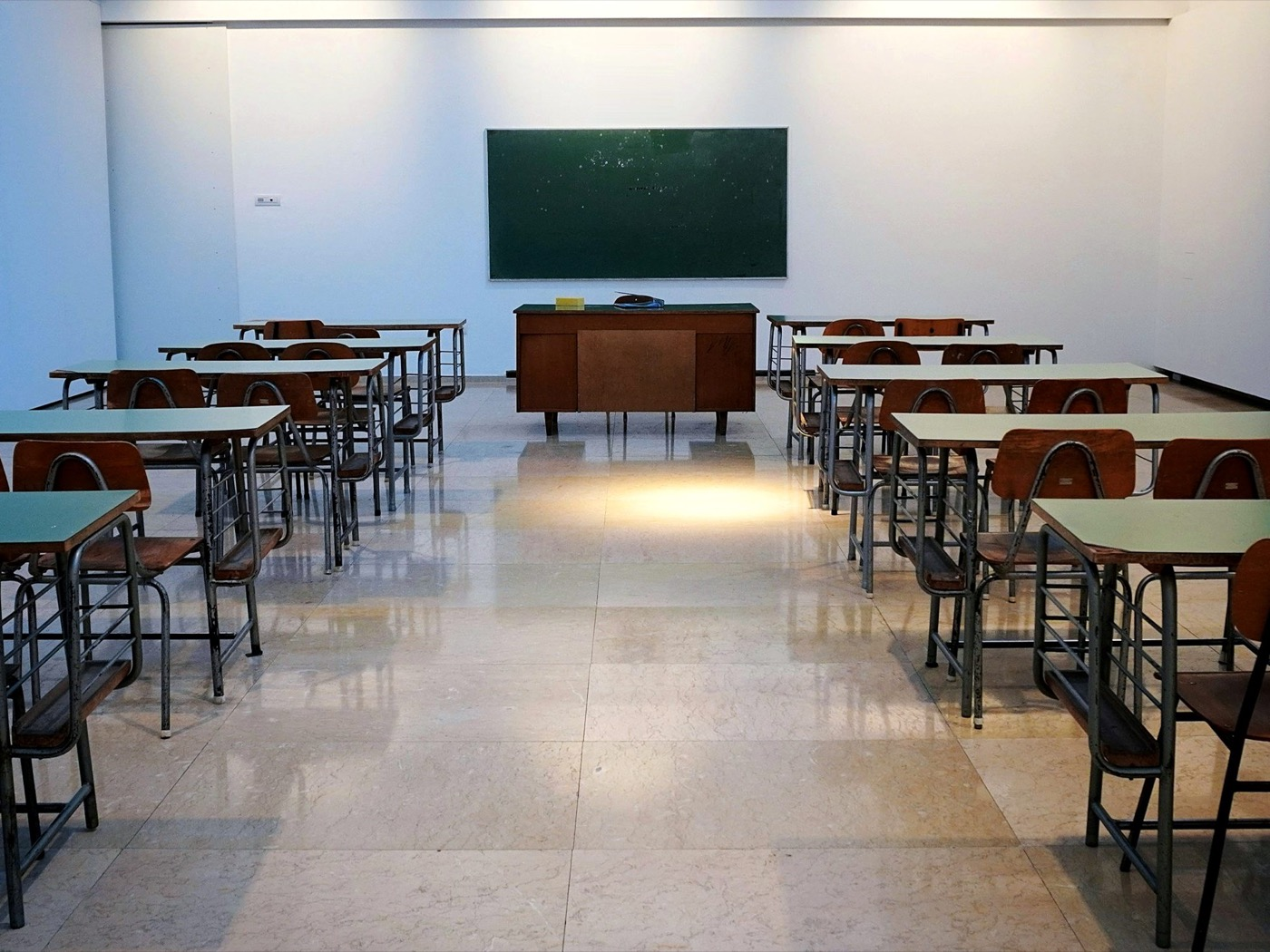An empty classroom with rows of desks and a chalkboard